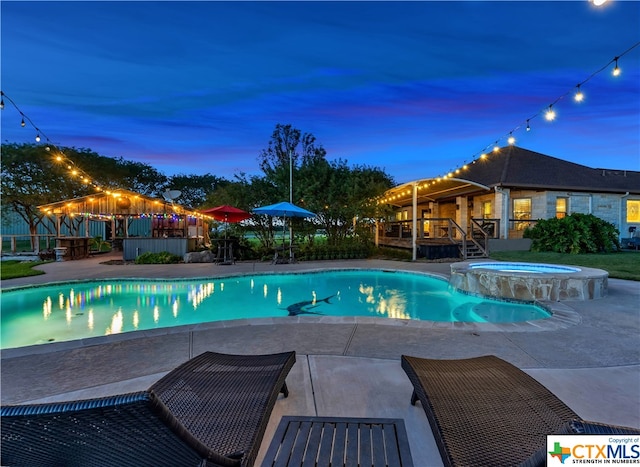 pool at dusk featuring a gazebo, an in ground hot tub, and a patio area