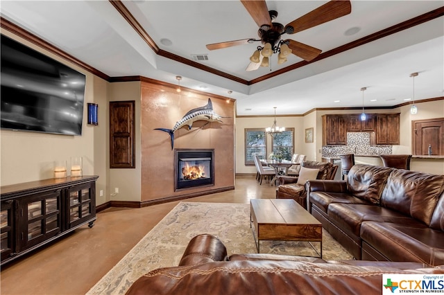 living room featuring a tray ceiling, ceiling fan with notable chandelier, a large fireplace, and crown molding