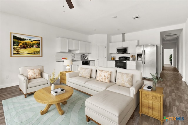 living room with dark hardwood / wood-style flooring, ceiling fan, and sink