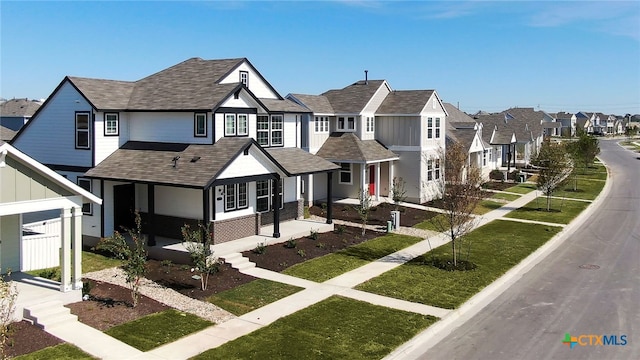 view of front of house with covered porch, a residential view, a shingled roof, and a front yard
