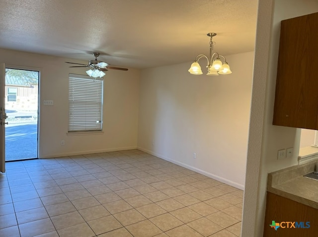 empty room with light tile patterned flooring, ceiling fan with notable chandelier, and a textured ceiling