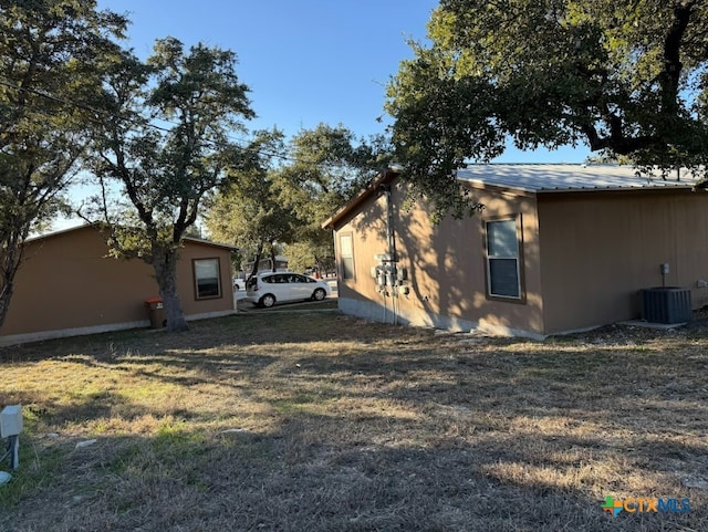 view of side of home featuring a lawn and central air condition unit