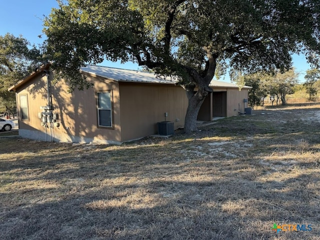 view of side of home with central AC unit and a lawn