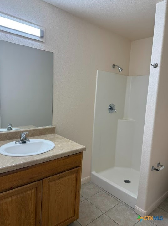 bathroom featuring vanity, tile patterned flooring, and a shower