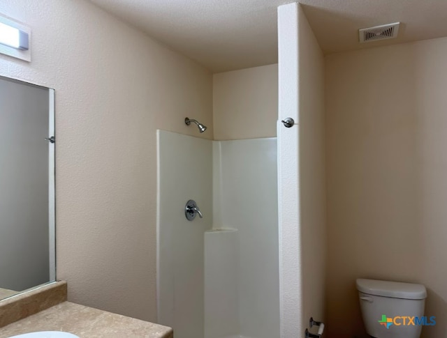 bathroom featuring a shower, vanity, and toilet