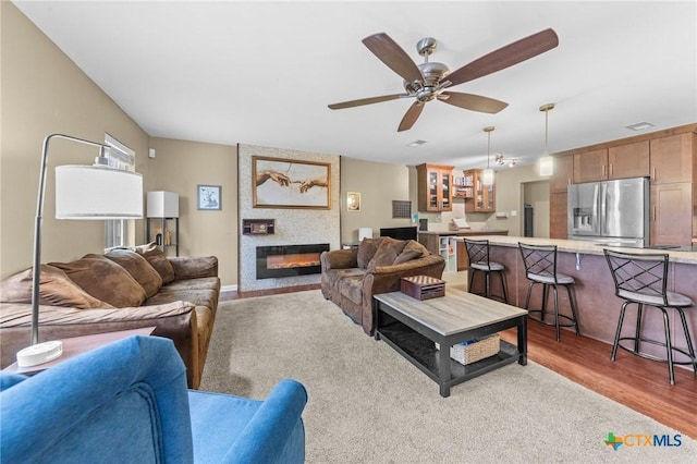 living room featuring light hardwood / wood-style floors, ceiling fan, and a fireplace