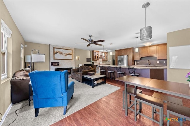 living room with ceiling fan, sink, and light hardwood / wood-style flooring