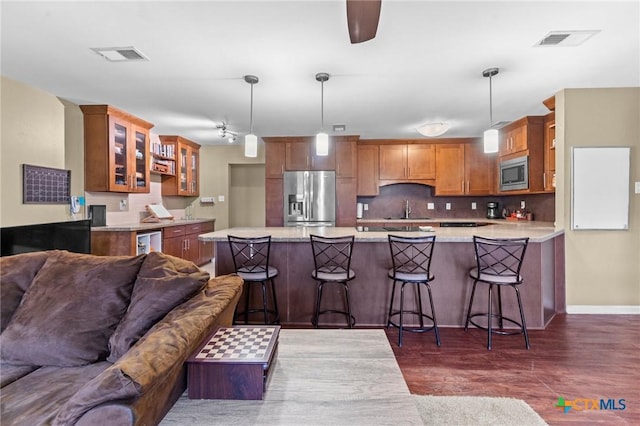 kitchen featuring appliances with stainless steel finishes, decorative light fixtures, dark wood-type flooring, sink, and a breakfast bar