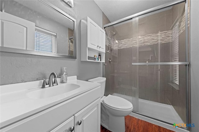 bathroom featuring hardwood / wood-style floors, toilet, walk in shower, and vanity