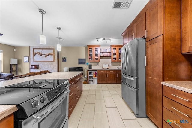 kitchen featuring hanging light fixtures, rail lighting, and appliances with stainless steel finishes