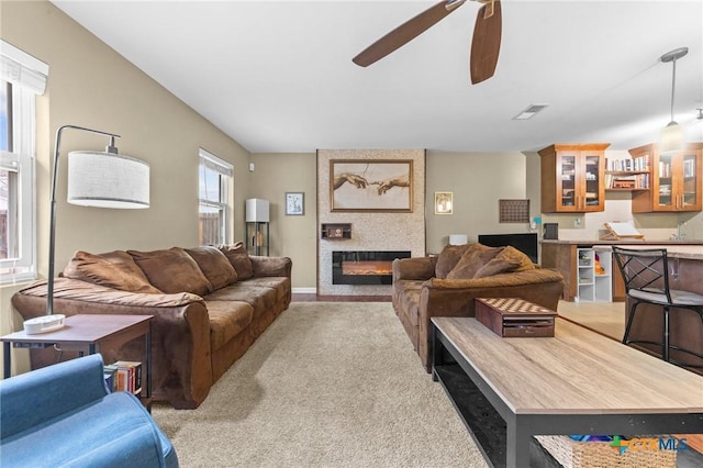 carpeted living room featuring a fireplace and ceiling fan