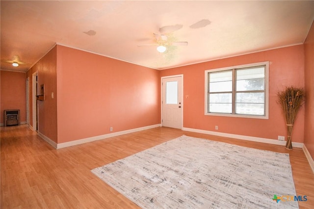empty room with light wood-style floors, a ceiling fan, baseboards, and crown molding