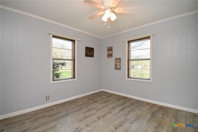 empty room with ceiling fan, plenty of natural light, wood finished floors, and crown molding
