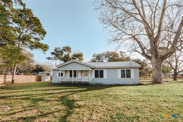 view of front of house with fence, covered porch, a front yard, and metal roof