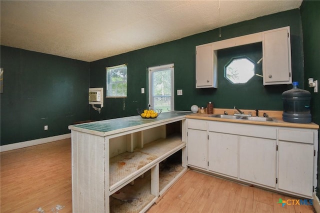 kitchen with a sink, light countertops, white cabinets, and light wood-style flooring