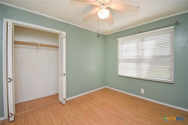 unfurnished bedroom with ceiling fan, a textured ceiling, wood finished floors, a closet, and ornamental molding