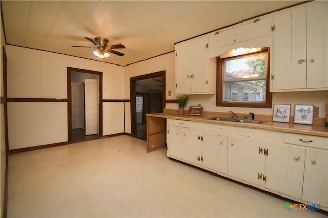 kitchen with light countertops, white cabinetry, a ceiling fan, and a sink