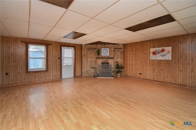 unfurnished living room with wood finished floors, baseboards, a drop ceiling, and a fireplace