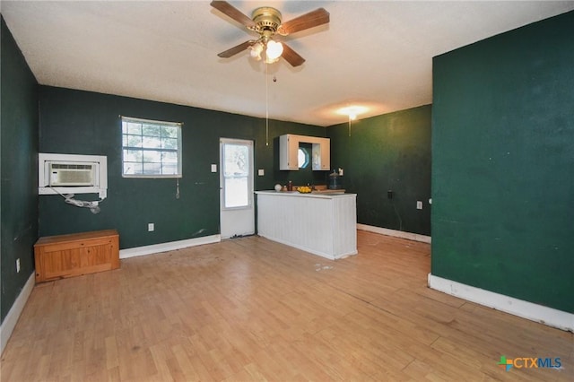 unfurnished living room with light wood-type flooring, a ceiling fan, baseboards, and a wall mounted AC