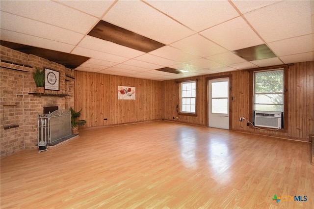 unfurnished living room featuring a healthy amount of sunlight, a drop ceiling, and light wood-type flooring
