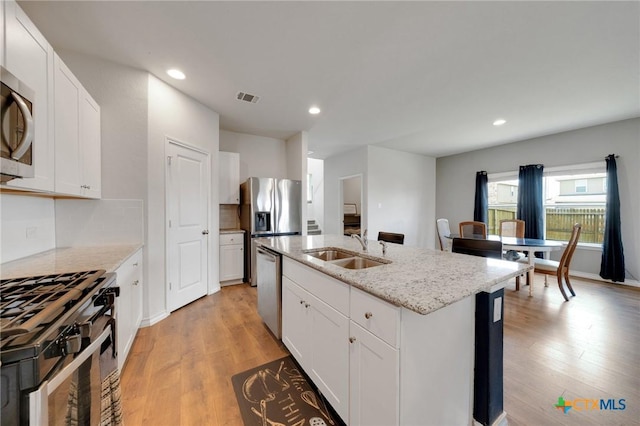 390 Lost Maples, New Braunfels, TX 78130 - kitchen with appliances with stainless steel finishes, recessed lighting, a center island with sink, light wood-style floors, and light stone countertops