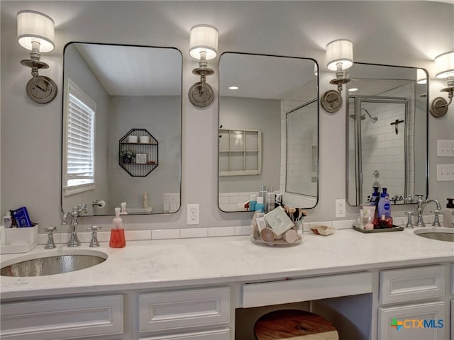 full bath with double vanity, tiled shower, and a sink