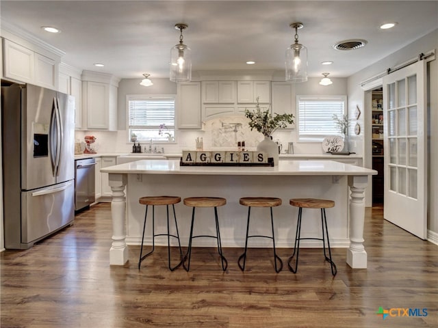kitchen featuring visible vents, white cabinetry, light countertops, a kitchen island, and appliances with stainless steel finishes