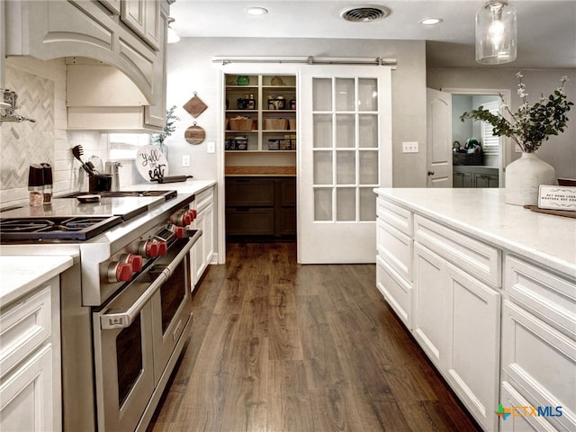 kitchen with double oven range, visible vents, backsplash, light countertops, and dark wood-type flooring