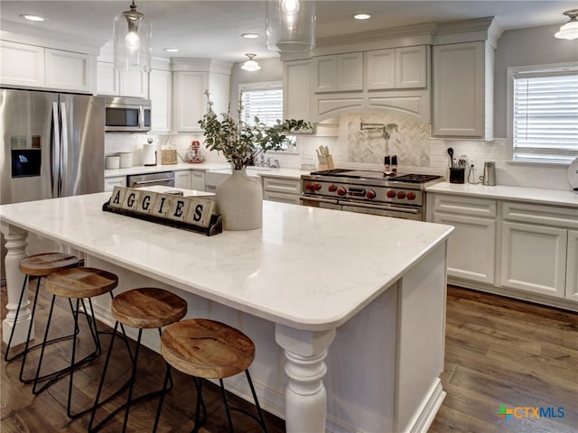 kitchen with a center island, tasteful backsplash, decorative light fixtures, appliances with stainless steel finishes, and premium range hood