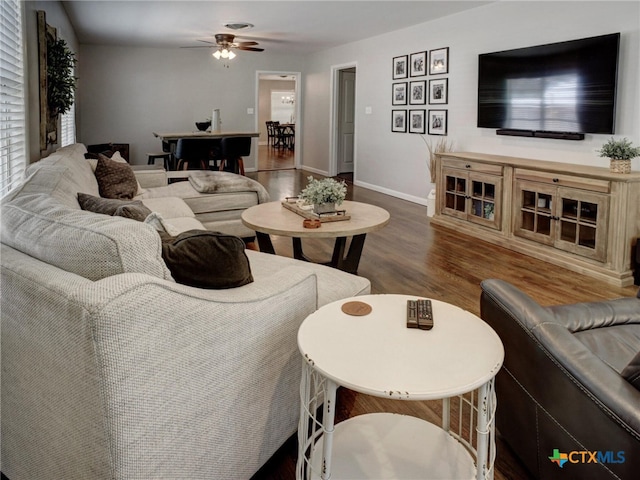 living area featuring wood finished floors, baseboards, and ceiling fan
