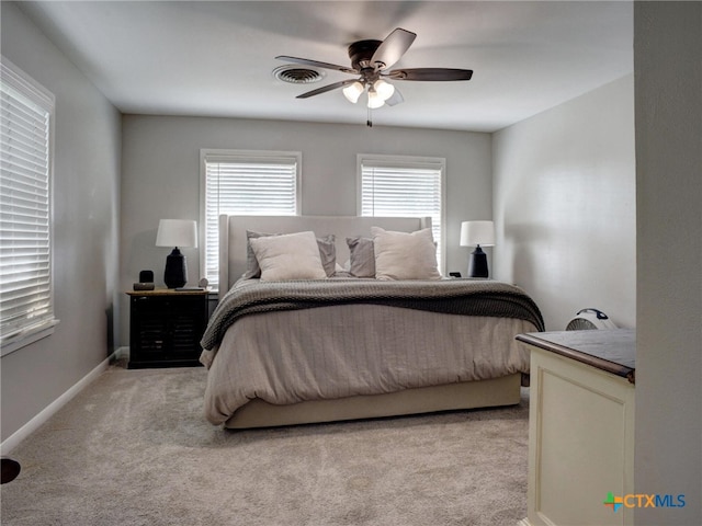 bedroom with baseboards, visible vents, a ceiling fan, and light colored carpet