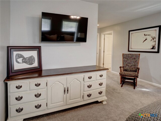 living area featuring light colored carpet and baseboards
