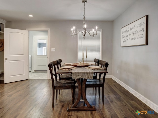 dining room featuring dark wood-type flooring, a healthy amount of sunlight, baseboards, and an inviting chandelier