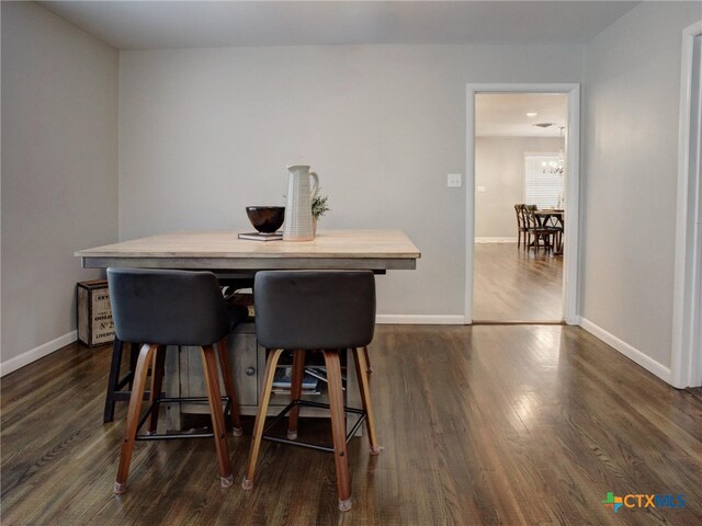 dining space featuring dark wood-type flooring, baseboards, and a notable chandelier