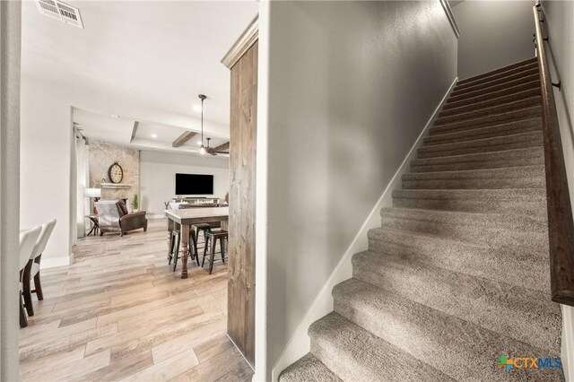 stairs with visible vents, wood finished floors, baseboards, ceiling fan, and a raised ceiling