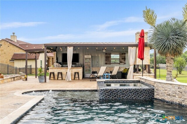 back of property featuring a patio, an in ground hot tub, fence, and outdoor dry bar