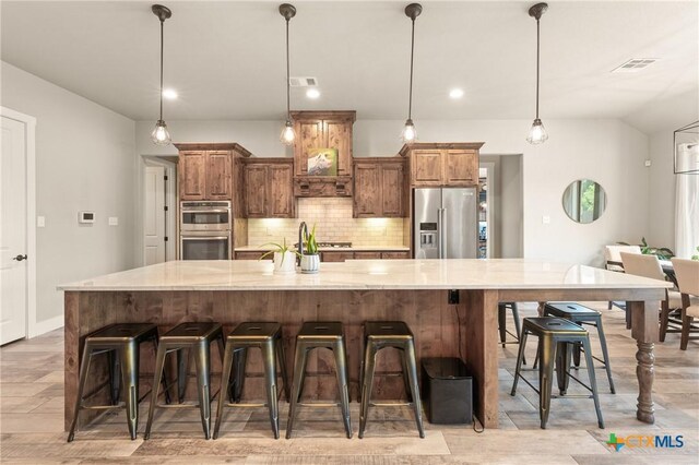 kitchen with visible vents, light wood-style flooring, backsplash, and stainless steel appliances