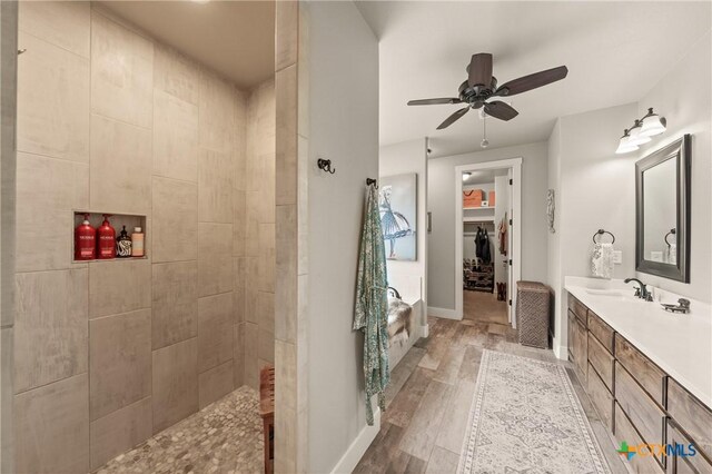 full bathroom with walk in shower, vanity, a ceiling fan, baseboards, and wood finished floors