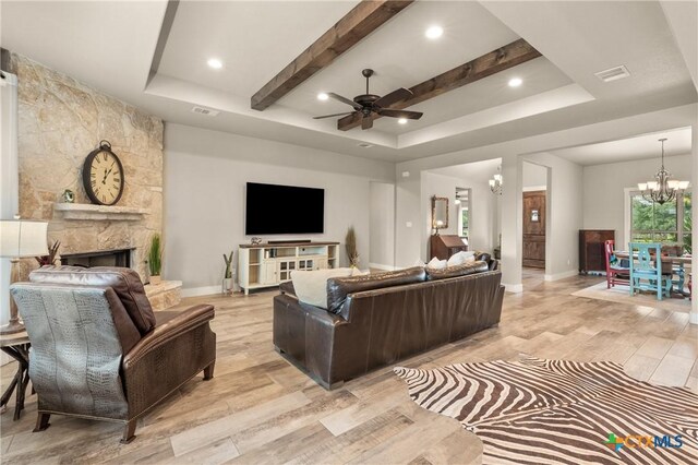living room with light wood-style floors, baseboards, ceiling fan with notable chandelier, and a tray ceiling