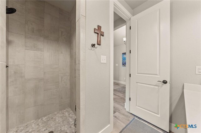 bathroom featuring baseboards and tiled shower