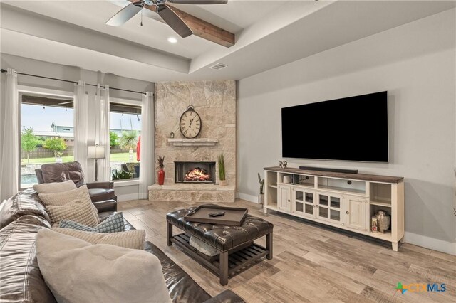 living room featuring a ceiling fan, visible vents, wood finished floors, a raised ceiling, and baseboards