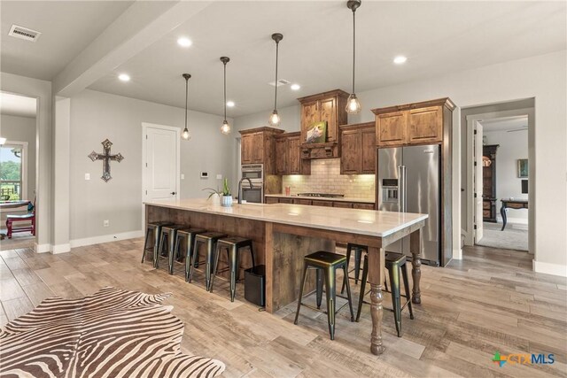kitchen featuring light countertops, a kitchen breakfast bar, stainless steel appliances, tasteful backsplash, and visible vents