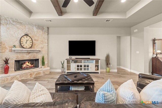 living area with a ceiling fan, beamed ceiling, visible vents, and wood finished floors