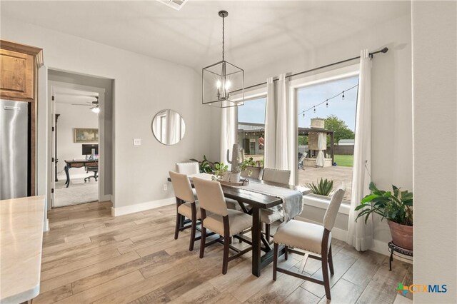 dining area featuring baseboards, ceiling fan with notable chandelier, and light wood finished floors