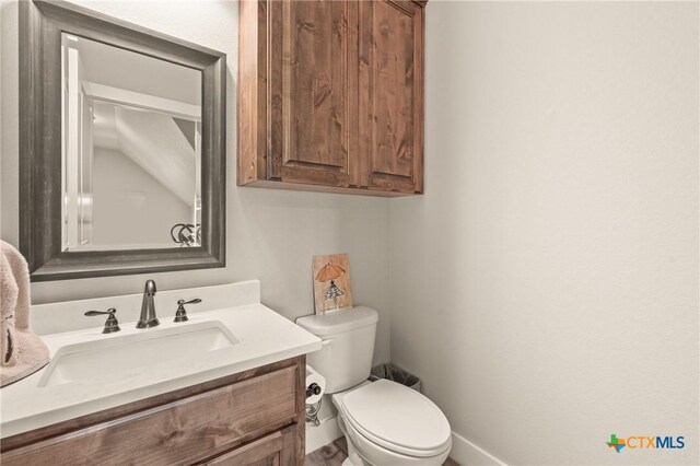 bathroom with vanity, baseboards, and toilet