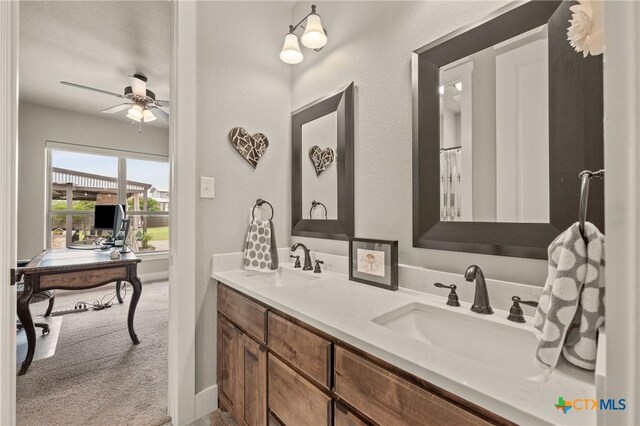 bathroom with a sink, baseboards, ceiling fan, and double vanity