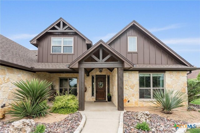 craftsman house featuring roof with shingles, board and batten siding, and stone siding