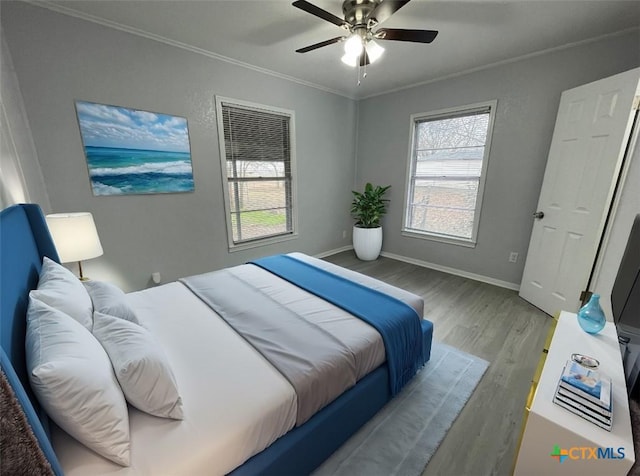 bedroom featuring a ceiling fan, crown molding, baseboards, and wood finished floors