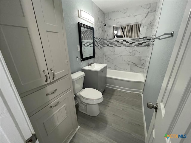 bathroom with a textured wall, toilet, wood finished floors, bathtub / shower combination, and vanity