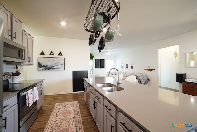 kitchen featuring a sink, stainless steel appliances, dark wood finished floors, and gray cabinets